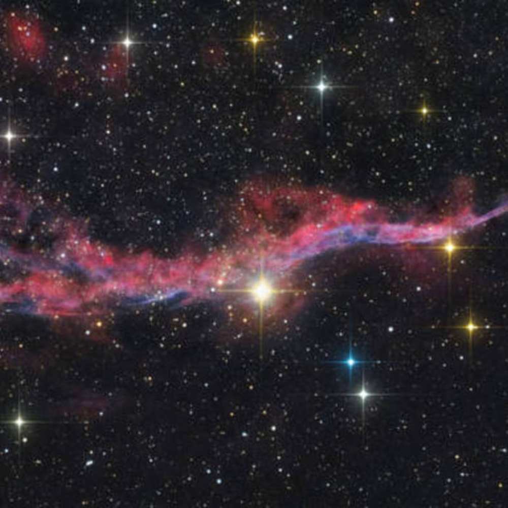 Color-enhanced deep space image showing the filamentary structure and glowing gases in the Cygnus Void, highlighting its vast emptiness and surrounding interstellar material.