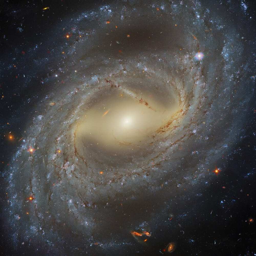 Hubble Space Telescope image of NGC 7329, a barred spiral galaxy with a bright central bulge, sweeping spiral arms, and regions of intense star formation glowing blue along the dust lanes.