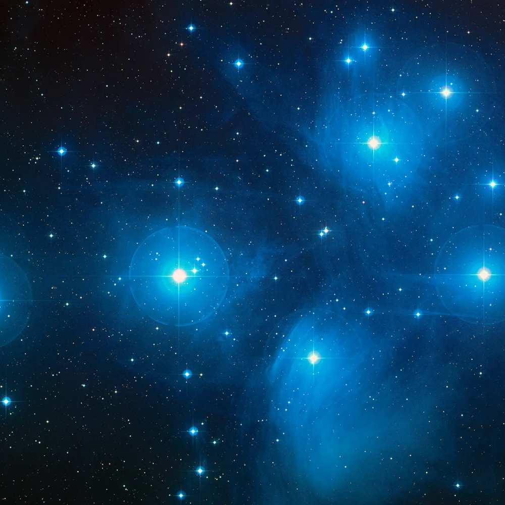 High-resolution image of the Ursa Major Cluster showing bright blue stars and galaxies within a loose spiral-rich structure spread across a faint nebular background.