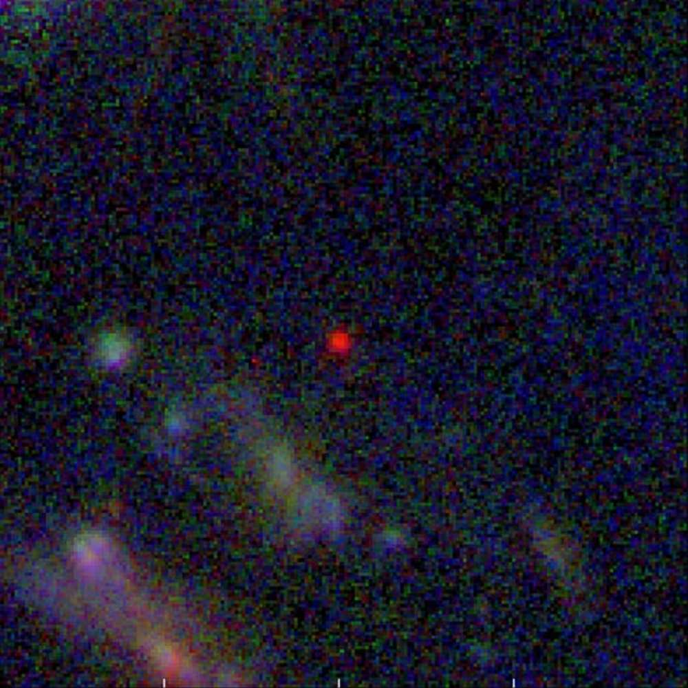Image showing one of the farthest visible galaxies captured through deep-field observations, appearing as a red dot due to extreme redshift caused by cosmic expansion.