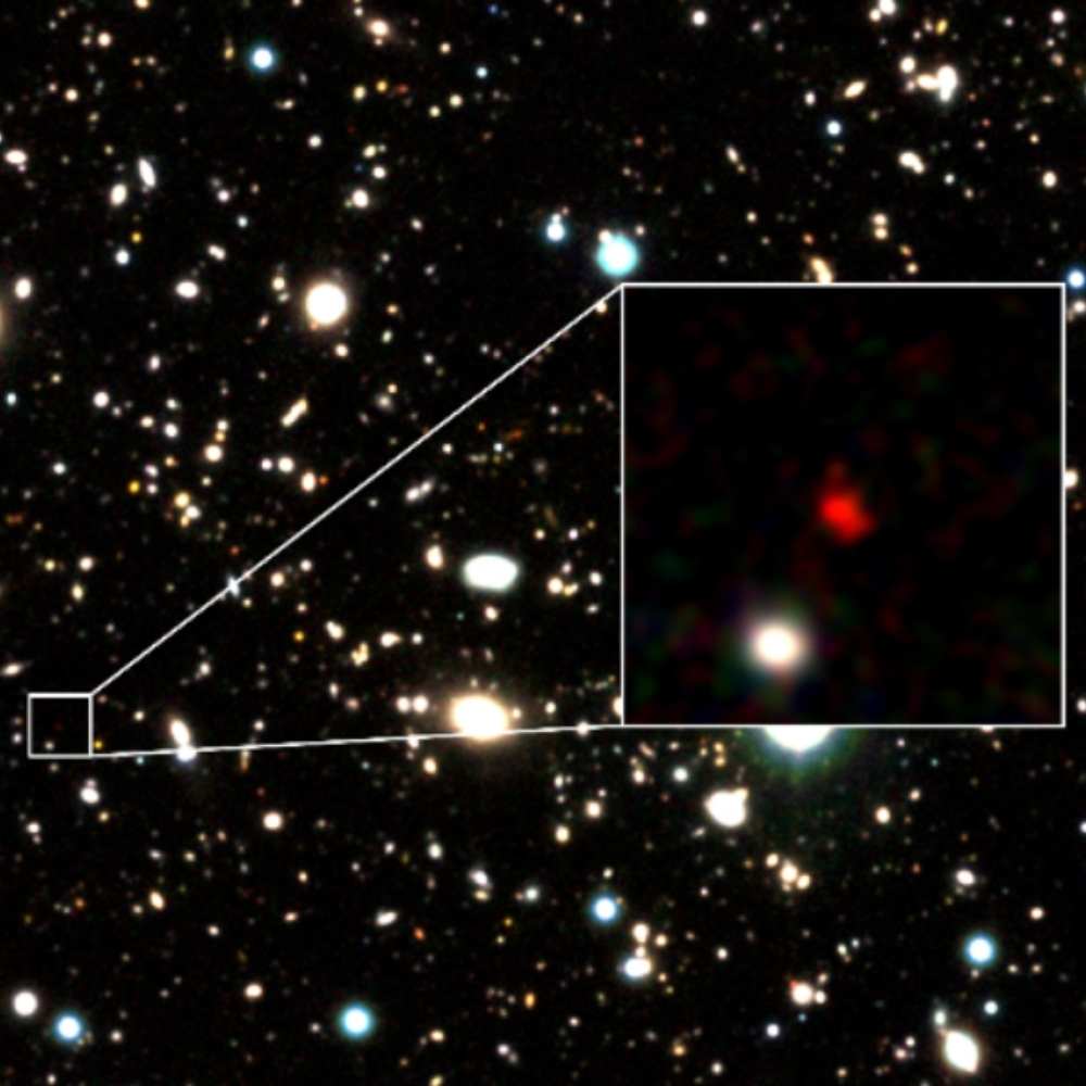 Zoomed-in view of HD1, the most distant known galaxy, marked in a deep-field image with a red hue indicating extreme redshift from the early universe.