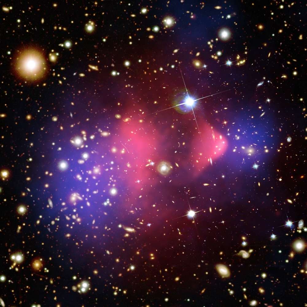Composite image of the Bullet Cluster showing galaxy collision, dark matter distribution in blue, and hot gas in pink using X-ray and optical data.