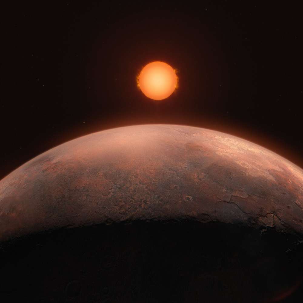 Artist’s impression of Barnard’s Star, a nearby red dwarf, illuminating the surface of a close-orbiting exoplanet with a dim orange glow.