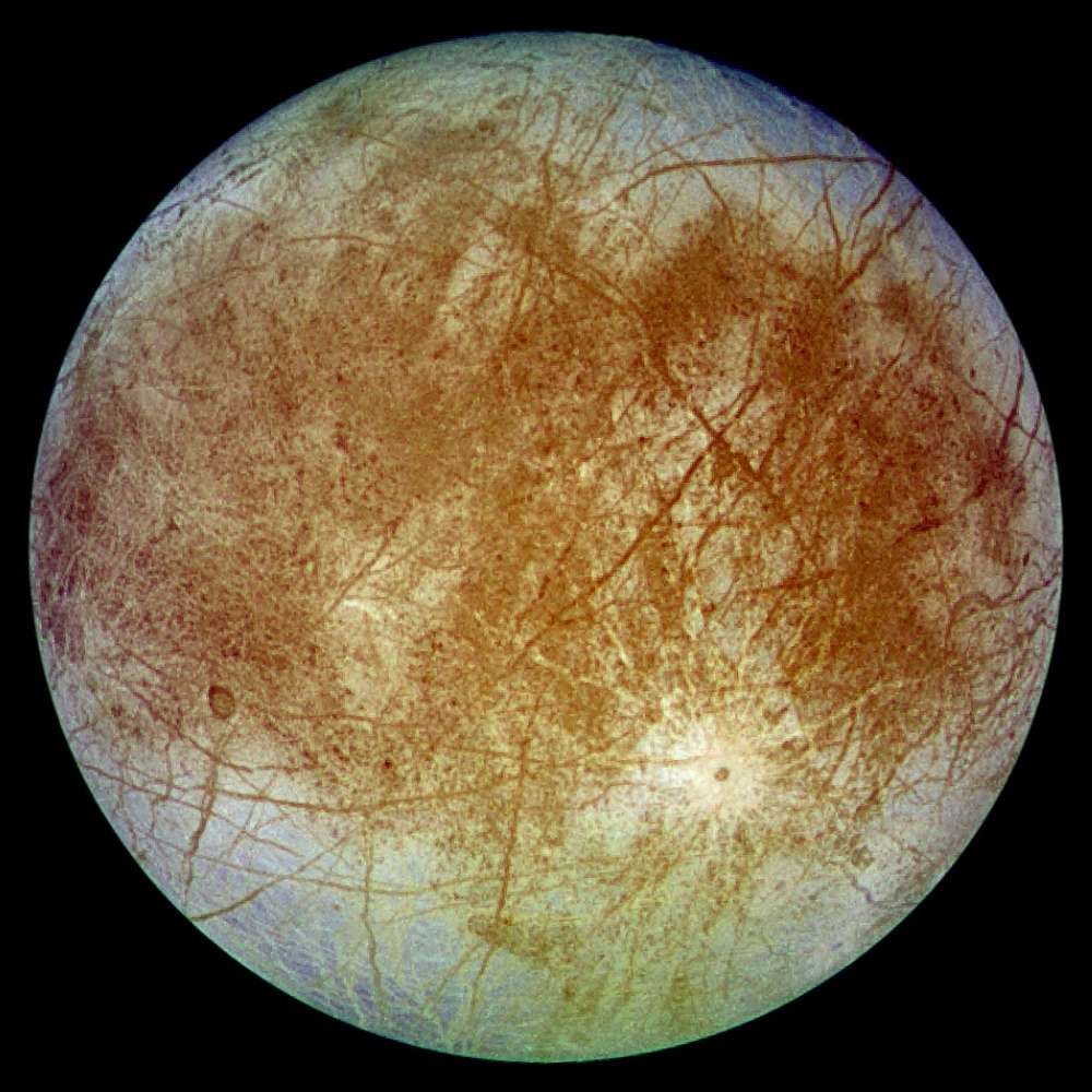 High-resolution image of Europa showing its smooth icy surface crossed by dark fractures and ridges, indicating a subsurface ocean beneath the moon’s frozen crust.