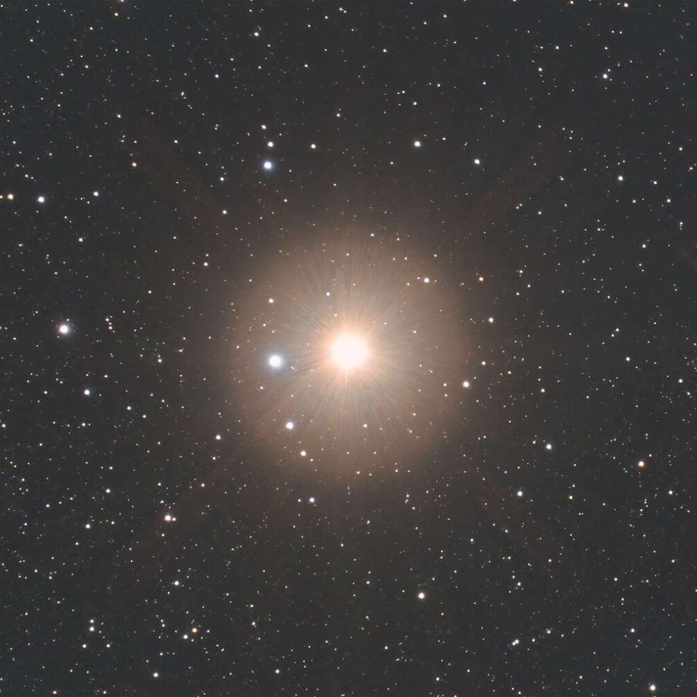 High-resolution star field showing Gacrux, a bright red giant star in the Crux constellation, glowing prominently with a soft halo among surrounding stars.