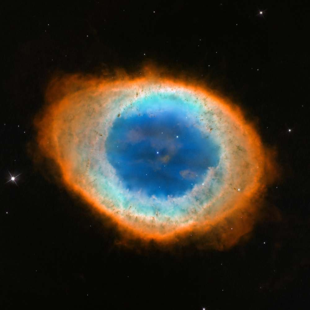 High-resolution Hubble image of the Ring Nebula (M57), showing its bright blue core surrounded by colorful ionized gas forming a glowing ring structure.