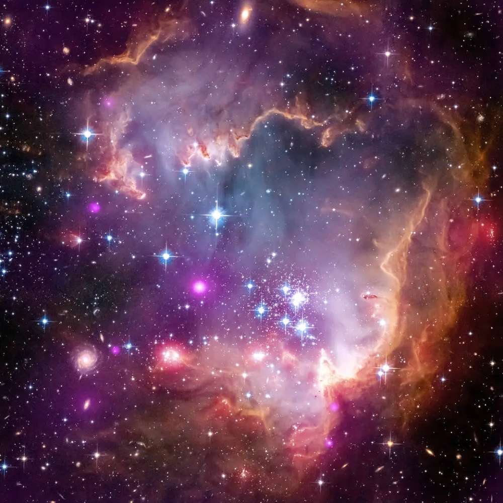 Colorful high-resolution image of a star-forming region in the Small Magellanic Cloud, showing bright young stars, glowing nebulae, and interstellar dust clouds.